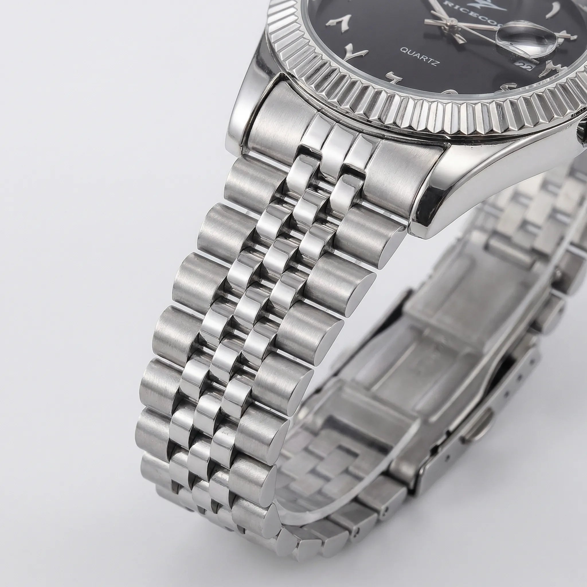 Detailed look at the polished stainless steel bracelet of a silver watch with an Arabic dial.