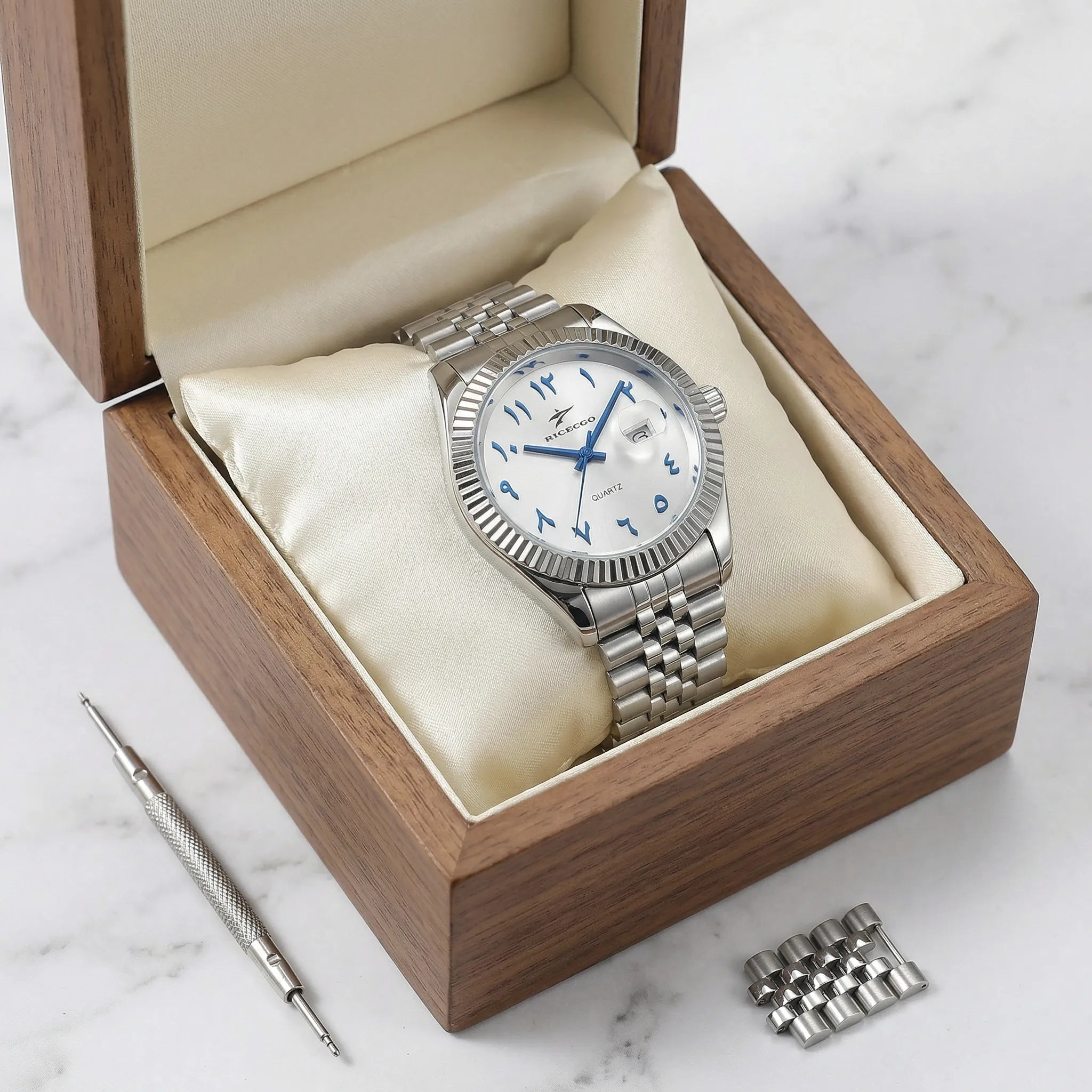 Detailed look at the polished stainless steel bracelet of a silver watch with a white Arabic dial.