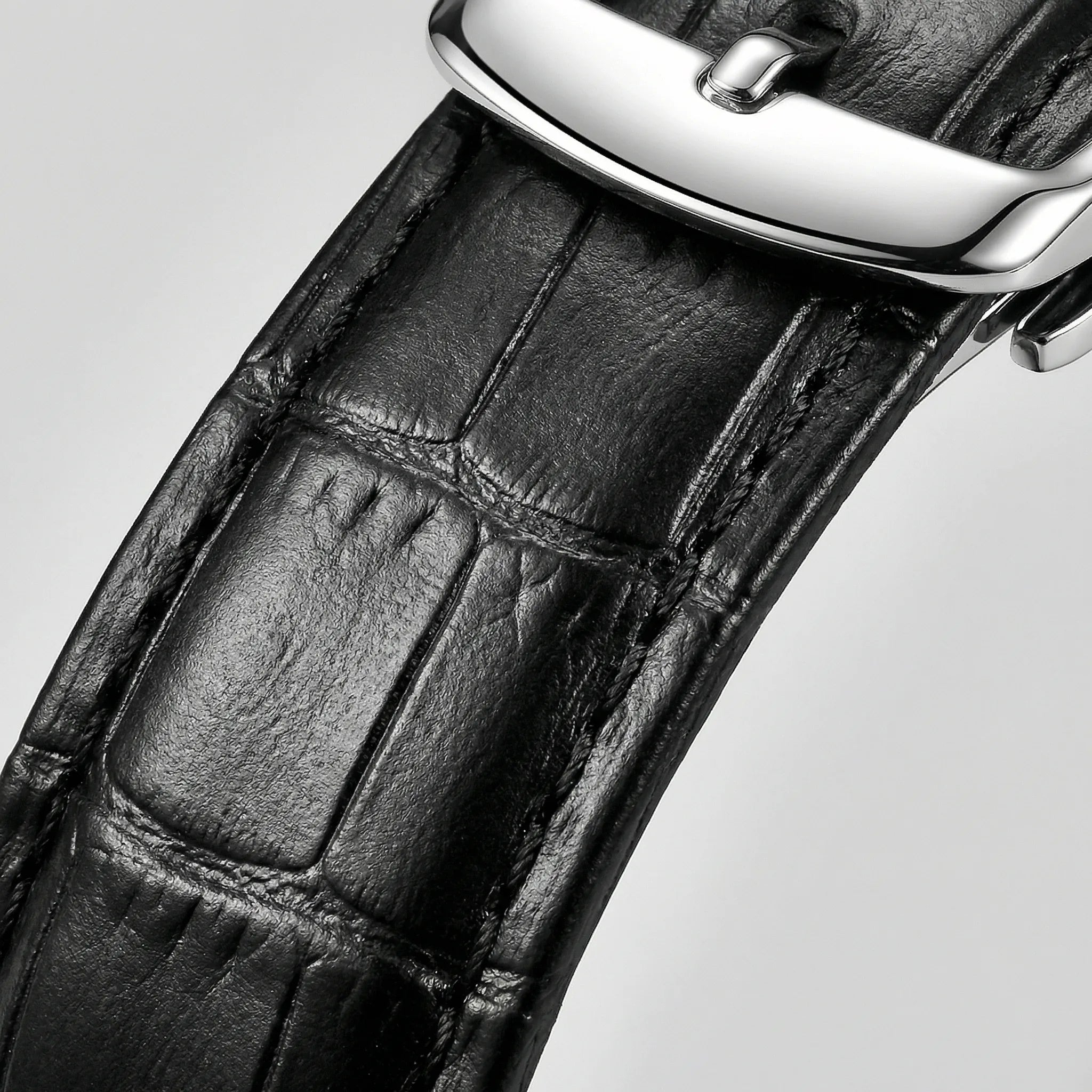 Detailed view of the precision hands on a silver watch with a black dial, a reliable quartz watch.