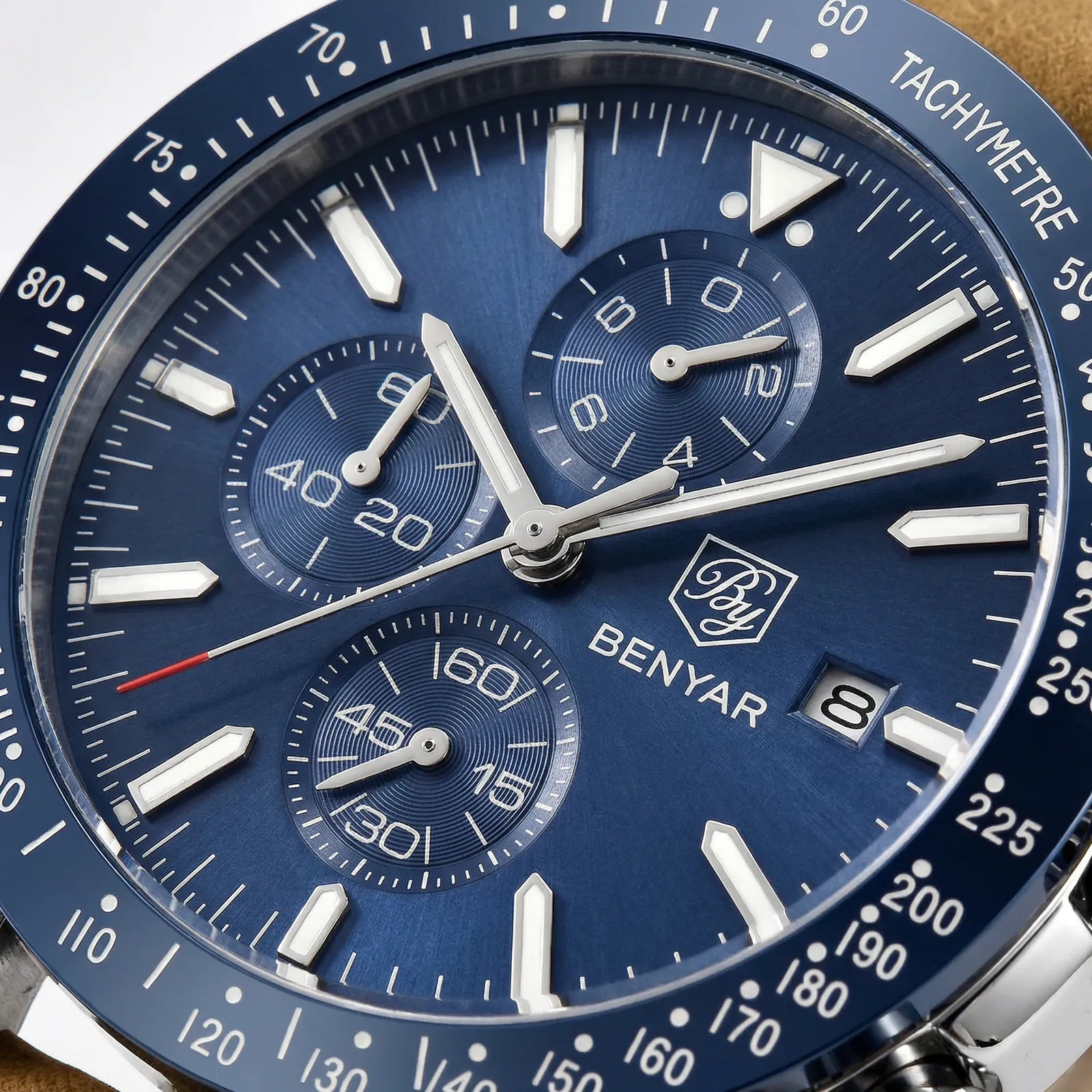 Close-up of the luminous hands and complex dial on a racing chronograph watch.